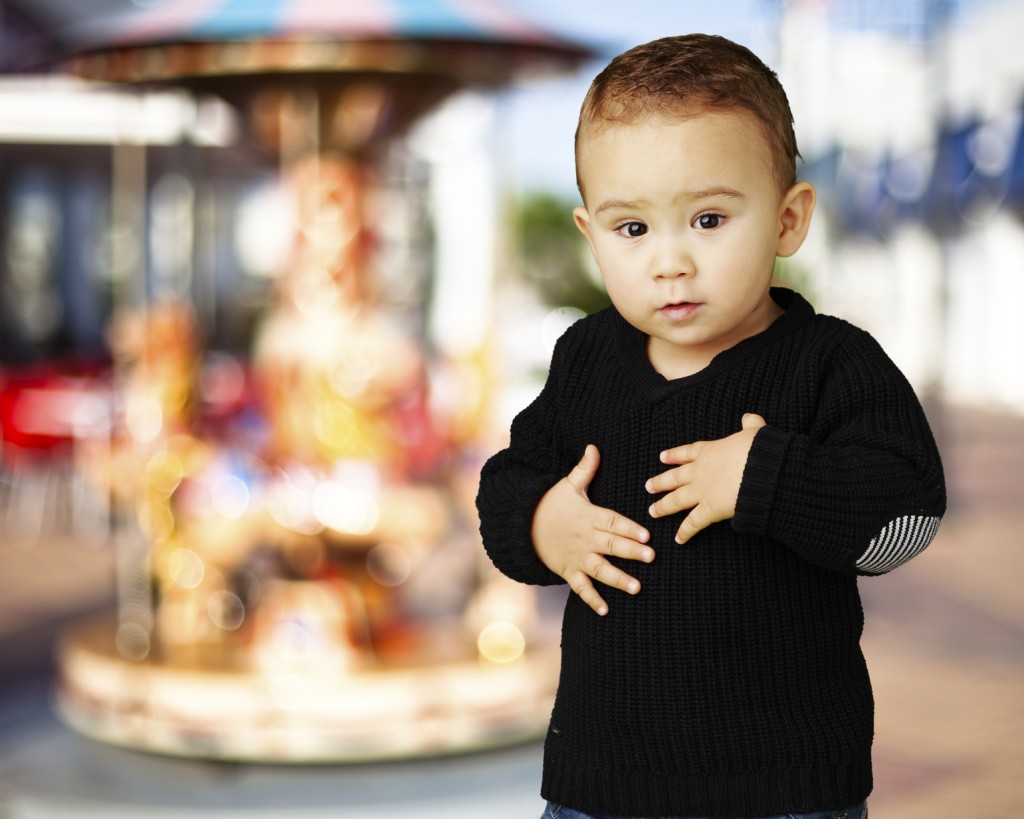 portrait of adorable kid touching his stomach against a carousel